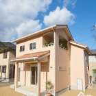 #生穂建設 柔らかなサーモンピンクの外壁に、洋風瓦の屋根がア...